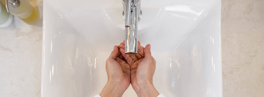 A woman is using a hotel faucet.